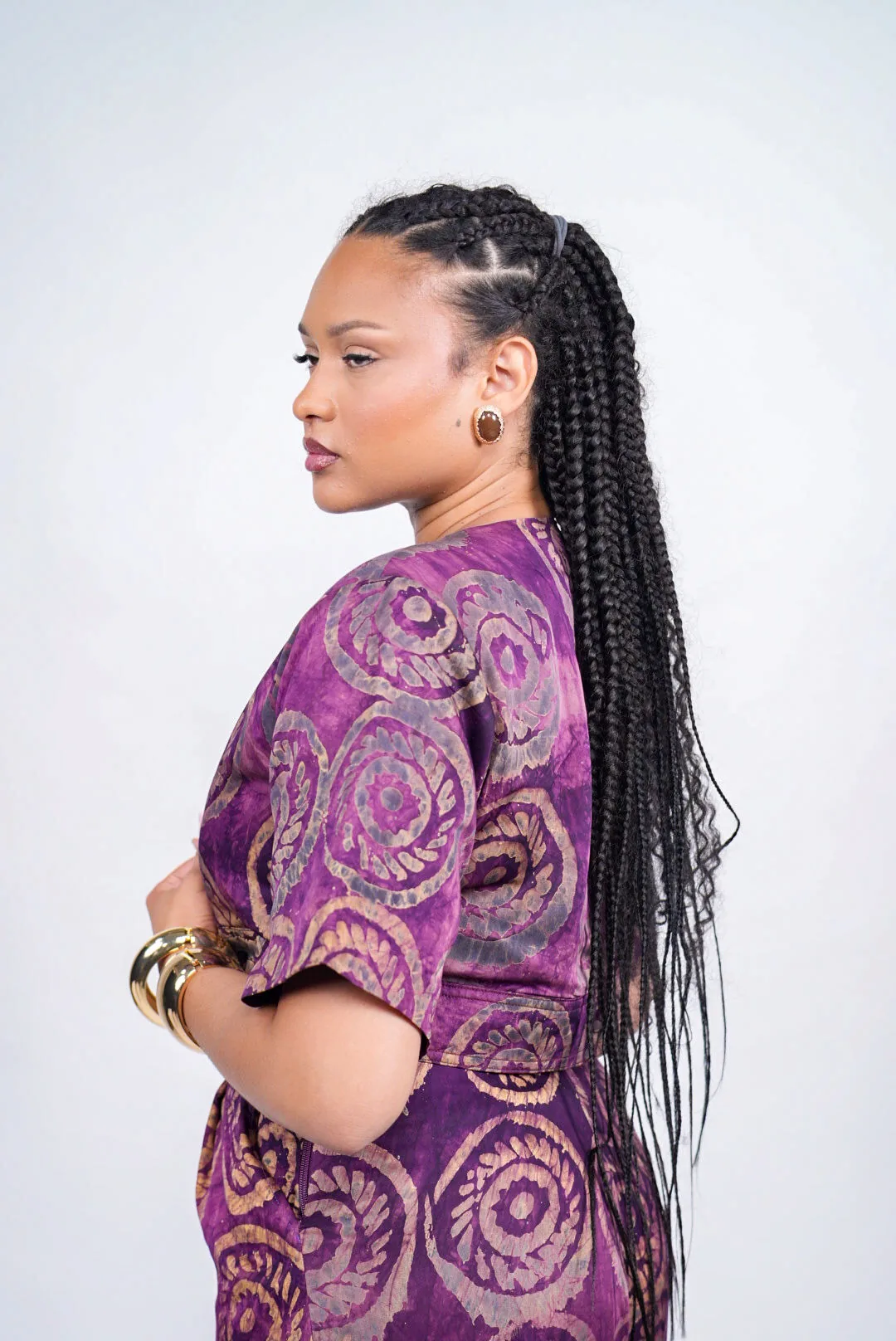 Femme de profil aux longues tresses, en veste Adire violette à motifs circulaires
