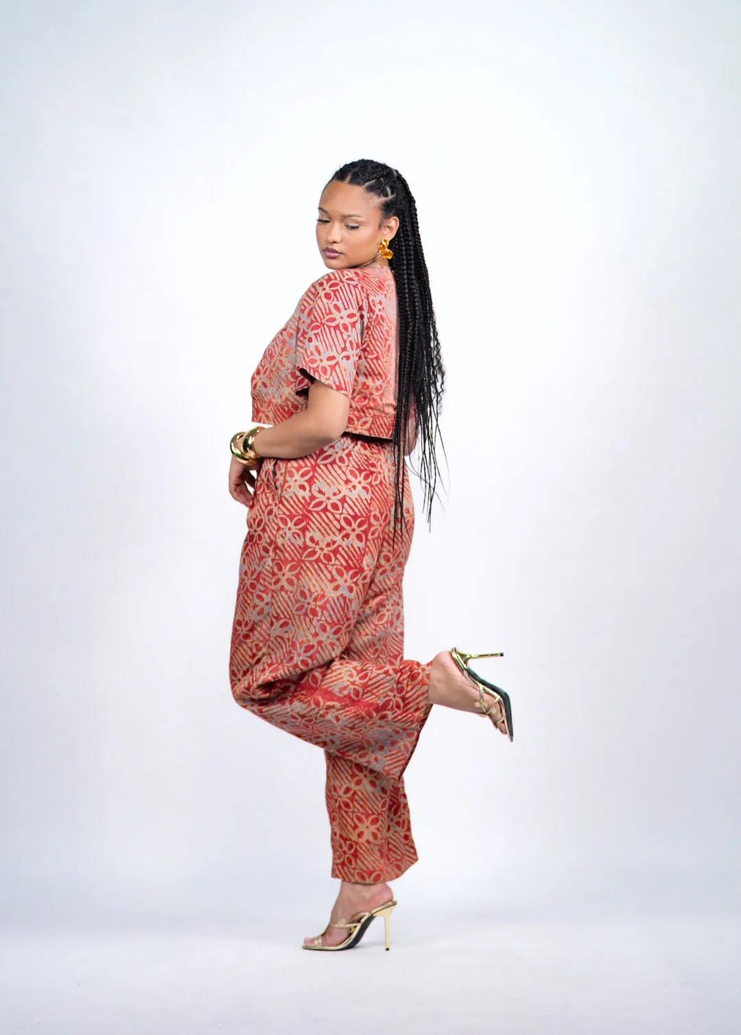 Femme en ensemble Adire corail, de profil, une jambe relevée