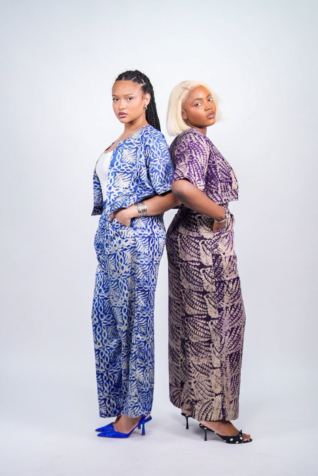 Deux femmes dos à dos, en ensembles HAYAH à motifs batik bleu et violet